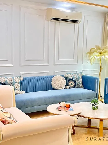 The combination of a classic off-white sofa with modern blue couches creates a balanced and interesting seating area in this refurbished living room.