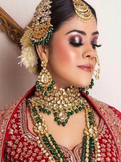 A bride wearing a layered Kundan and emerald set with a red lehenga. The side-passa adds a touch of Mughal elegance.