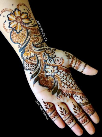 A beautiful Arabic henna design that combines floral and paisley elements. The pattern is elegant and flows nicely from the wrist to the fingers.