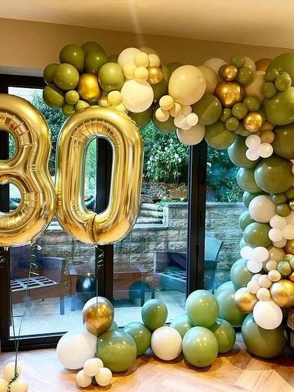 An organic balloon arch in olive green, white, and gold for a sophisticated 30th birthday celebration.