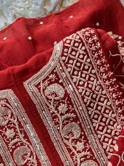 A detailed close-up of the neckline on our Sindoori Red Anarkali. This view highlights the precise hand-embroidery, combining traditional Chikankari with shimmering Kutdana and sequins.