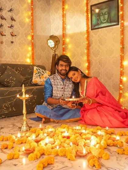 A sweet and intimate moment from a couple's Diwali shoot, as she rests her head on his shoulder, both seated amidst a sea of glowing diyas.