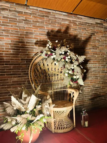Another view of the decorated peacock chair. The combination of the natural rattan, pampas grass, and white flowers against the brick wall is the epitome of boho-chic wedding style.