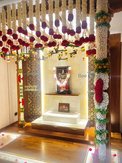 The same pooja room from a different angle, showing the beautiful ceiling hangings and the pillar garlands. We ensure every part of the space is decorated to perfection.