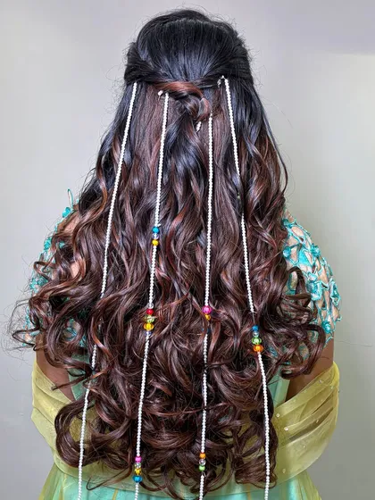 The hairstyle for this look was soft waves with a half-updo, adorned with long, beaded accessories for a bohemian touch.