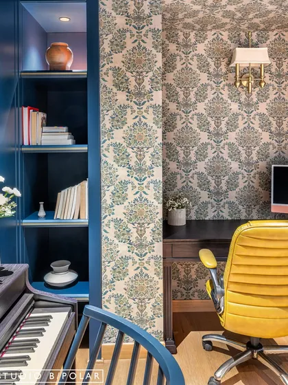 The music room at Sunlit Serenity is separated from the dining area by an elegant glass partition. The room itself has a moody, dark aesthetic with deep navy walls and patterned wallpaper.