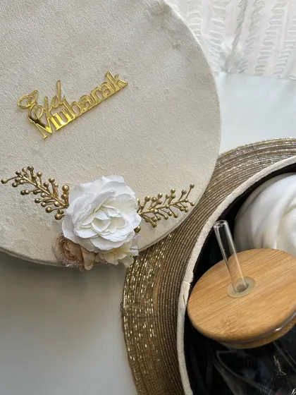 An open view of the velvet Eid box, revealing a glass tumbler and a rolled scarf inside.