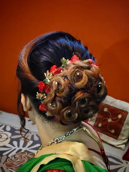 A top-down view of the creative bun, showing the detailed curling technique and the beautiful color dimension from the hair highlights.