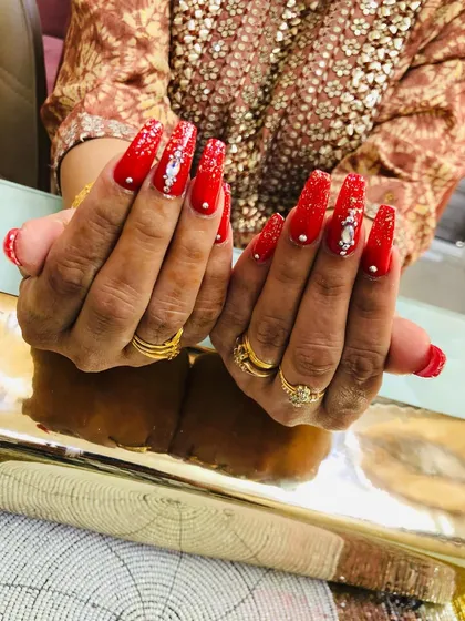 For the bride who loves red. This set features long, square extensions with a vibrant red, accented with glitter and intricate stone and pearl work.