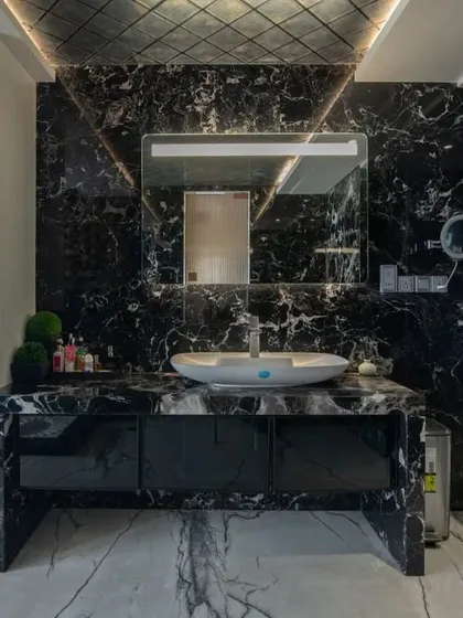 We believe bathrooms should be personal sanctuaries. This master bathroom uses dramatic black marble, bookmatched for continuous veining, and strategic lighting to create a bold, spa-like experience that feels both opulent and intimate.