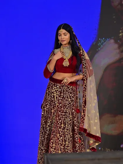 A full-body shot on the runway, where the makeup needs to make an impact from a distance. The bold lip and strong eyes ensure her face is a focal point.