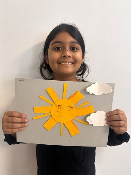 A beautifully made paper sun, with carefully cut rays and perfectly placed clouds.