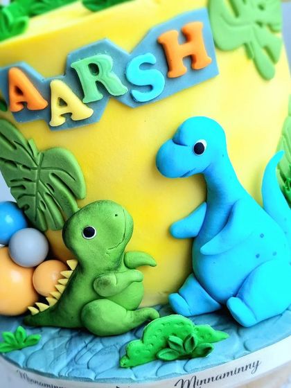 A close-up of the cute, sitting fondant dinosaurs on the yellow dinosaur cake.