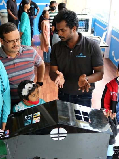 An instructor explains a smart home prototype to a family at our RoboExpo. Our projects often model real-world technologies that students see in their daily lives.