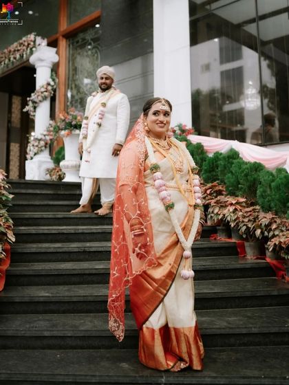 A beautiful portrait of the couple on the steps of their venue. The bride's elegant saree and the groom's traditional white attire create a timeless and graceful image.