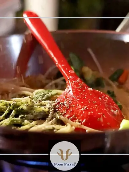 A close-up shot of pesto spaghetti being tossed in a pan over the flame. This image captures the freshness and dynamic nature of my live pasta counters.