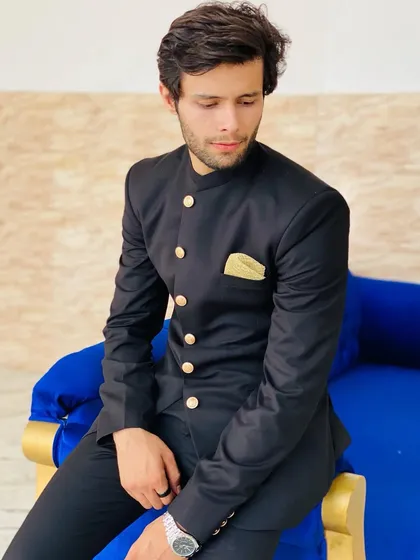 A stylish groom in a black Jodhpuri suit with gold buttons. This look is regal and perfect for a grand reception.