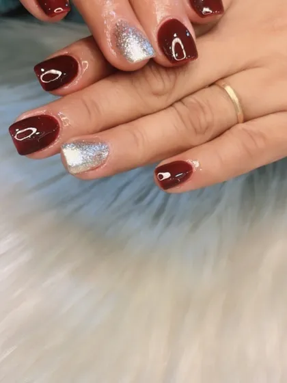 A classic holiday or party look with deep maroon nails and a sparkling silver accent nail.