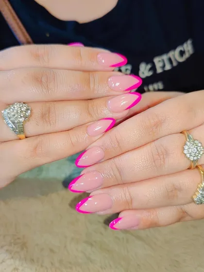 A classic French manicure with a bold twist. The neutral base is paired with a vibrant, hot pink tip for a fun and modern pop of color.