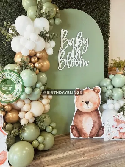 A charming "Baby Bloom" woodland-themed baby shower, featuring a sage green backdrop against a faux greenery wall. I included cute fox and bear cutouts and a balloon garland in gold, white, and green for a natural, rustic feel.