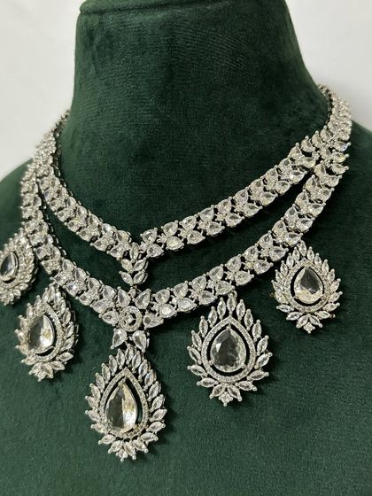 A layered American diamond necklace with intricate details and large pendants. This rental set is designed for maximum sparkle.