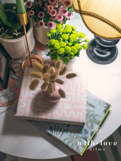 A tabletop detail from 'The Conservatory', with a mix of books, candles, and flowers.
