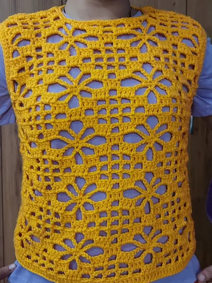 Here is the Argalia Bloom Top, a bright and cheerful sleeveless vest. The openwork floral pattern is perfect for layering over a simple tee or camisole.