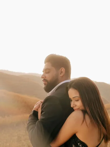 A peaceful embrace in a golden field, with the sun creating a beautiful flare. This image feels warm, serene, and deeply romantic.
