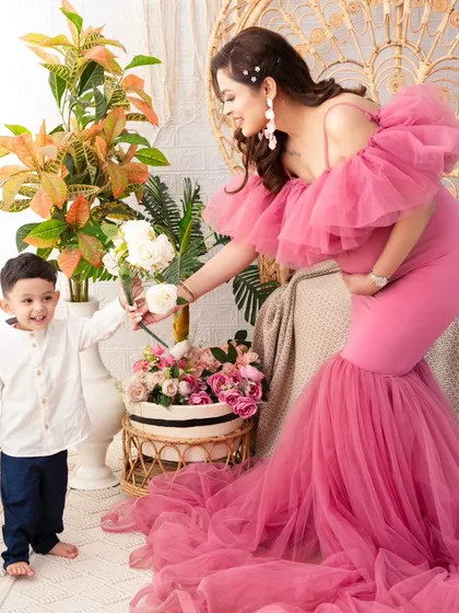 A tender moment between mother and son. Dressed in a magnificent pink tulle gown, this mother-to-be shares a flower with her son, a beautiful symbol of their growing love.