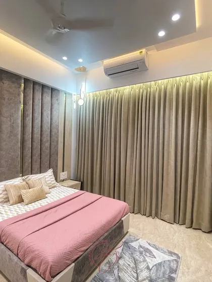 This bedroom features a warm and inviting design with a plush, vertically-paneled headboard in a soft brown fabric. The pink bedding adds a gentle pop of color, creating a cozy and chic atmosphere.