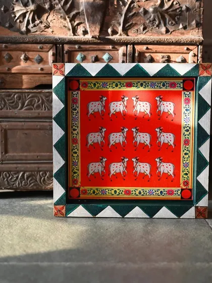The top block, featuring a pattern of cows against a vibrant red background, a classic motif in Pichwai art that symbolizes devotion.