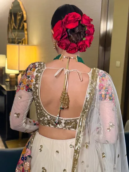 A close-up of my signature floral bun, featuring a crown of vibrant red roses woven into a sleek, classic updo. This style is a bold and romantic choice that adds a dramatic pop of color to any bridal ensemble.
