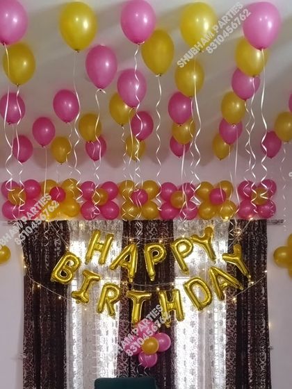 A simple and cheerful birthday decoration with pink and yellow balloons.
