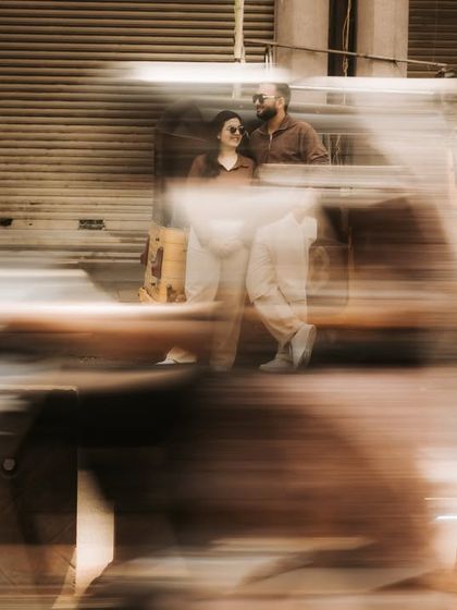 A creative shot using motion blur to capture the energy of a bustling street. The couple remains in focus, a calm center in the midst of the city's movement.