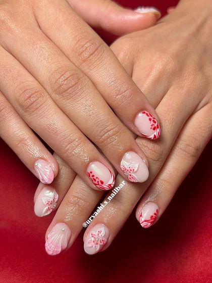 For this look, I used a builder gel overlay, also known as BIAB, on natural nails to add strength. Then I created this beautiful design with red patterns and 3D white flowers for a pop of color and texture.