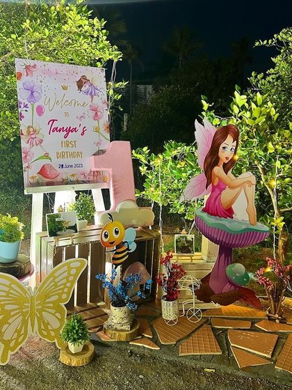 A charming welcome corner for the fairy-themed party, with a personalized sign, a fairy cutout sitting on a mushroom, and other woodland creature props.