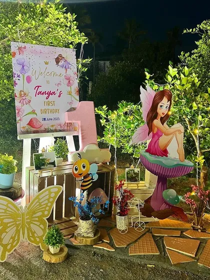 A charming welcome corner for the fairy-themed party, with a personalized sign, a fairy cutout sitting on a mushroom, and other woodland creature props.