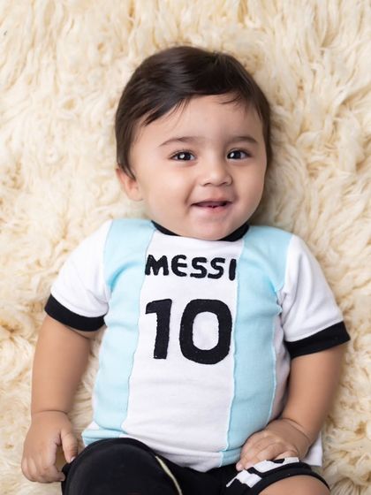A simple, beautiful close-up portrait of the baby in his football jersey, capturing his bright and happy smile.