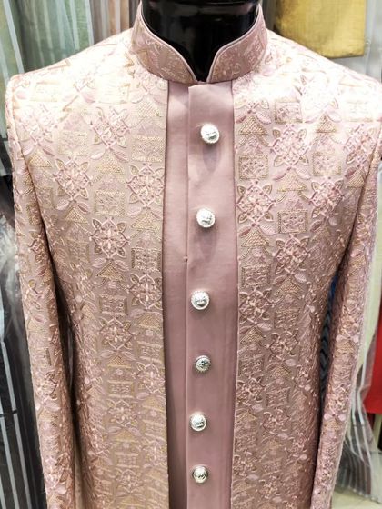 A close-up of a dusty rose open sherwani, focusing on the texture of the embroidered fabric and the elegant satin inner layer.
