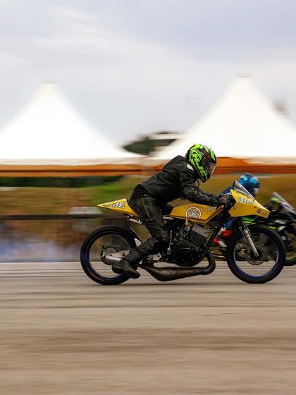 A classic yellow two-stroke race bike, likely a modified Yamaha RX, competing on the strip. We celebrate all eras of motorsport, from modern superbikes to iconic classics.