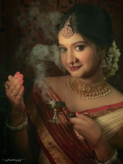 Portraits from a makeup shoot, showcasing a model in a classic red and cream saree. The images highlight the flawless makeup and traditional styling in a beautiful garden setting.