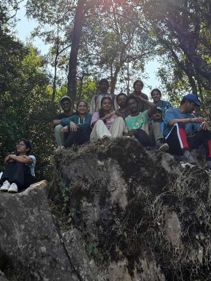 The group taking a rest on a large rock, surrounded by the beautiful forest.