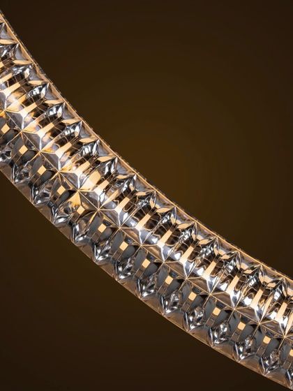 A macro shot of the Luminora pendant's surface, revealing the detailed texture and torsion effect that catches the light. This emphasizes the craftsmanship and ornamental quality of the design.