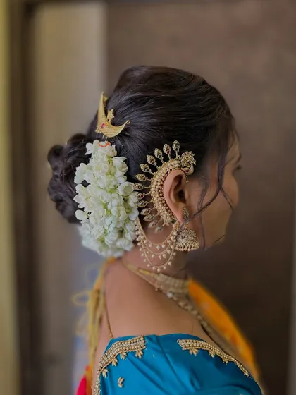 A side view showcasing the intricate ear cuff ('kaan vel') and the floral bun, which are key elements of a traditional bridal look.
