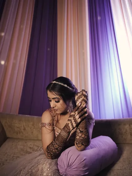 A quiet, contemplative moment amidst the celebrations, showcasing the detailed mehndi that covers her hands and arms.