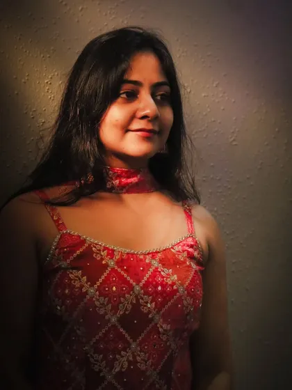 A beautifully lit portrait of the bride during her Mehendi or Sangeet event. The warm, dramatic lighting highlights her features and the rich color of her outfit.