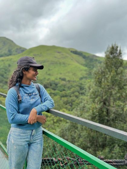 A trekker enjoying a moment of calm on a bridge, with the beautiful green hills in the background.