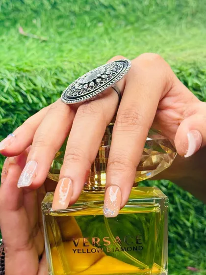 A close-up showcasing the sheer nude polish with a light dusting of glitter on long, natural-shaped nails, creating a delicate and ethereal look.