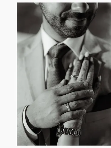 A close-up, black and white shot of the couple's hands, now adorned with engagement rings. This photo is a simple, powerful symbol of their commitment.
