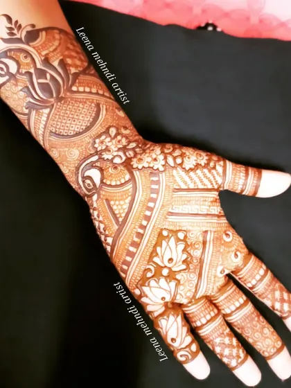 A single-hand view of an intricate siders design. The pattern features a prominent peacock and is filled with detailed floral and geometric elements.